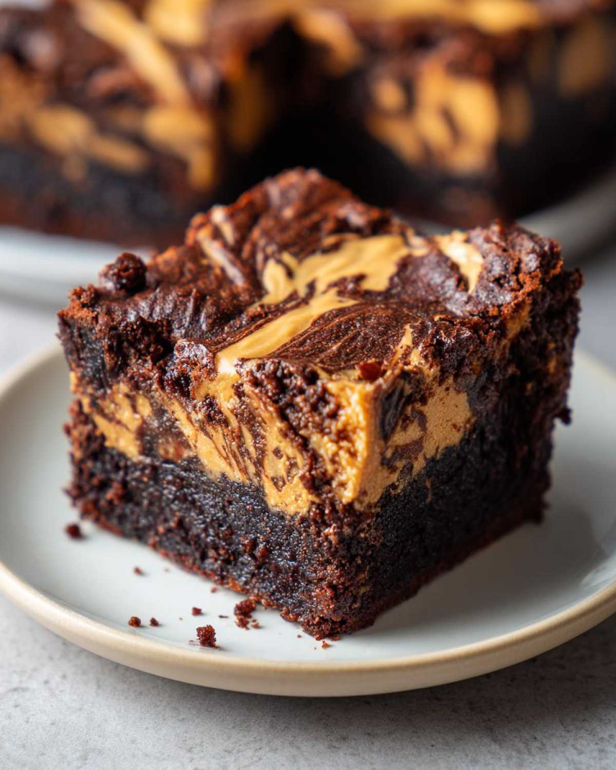 A close-up of a fudgy peanut butter swirl brownies square served on a small white plate.