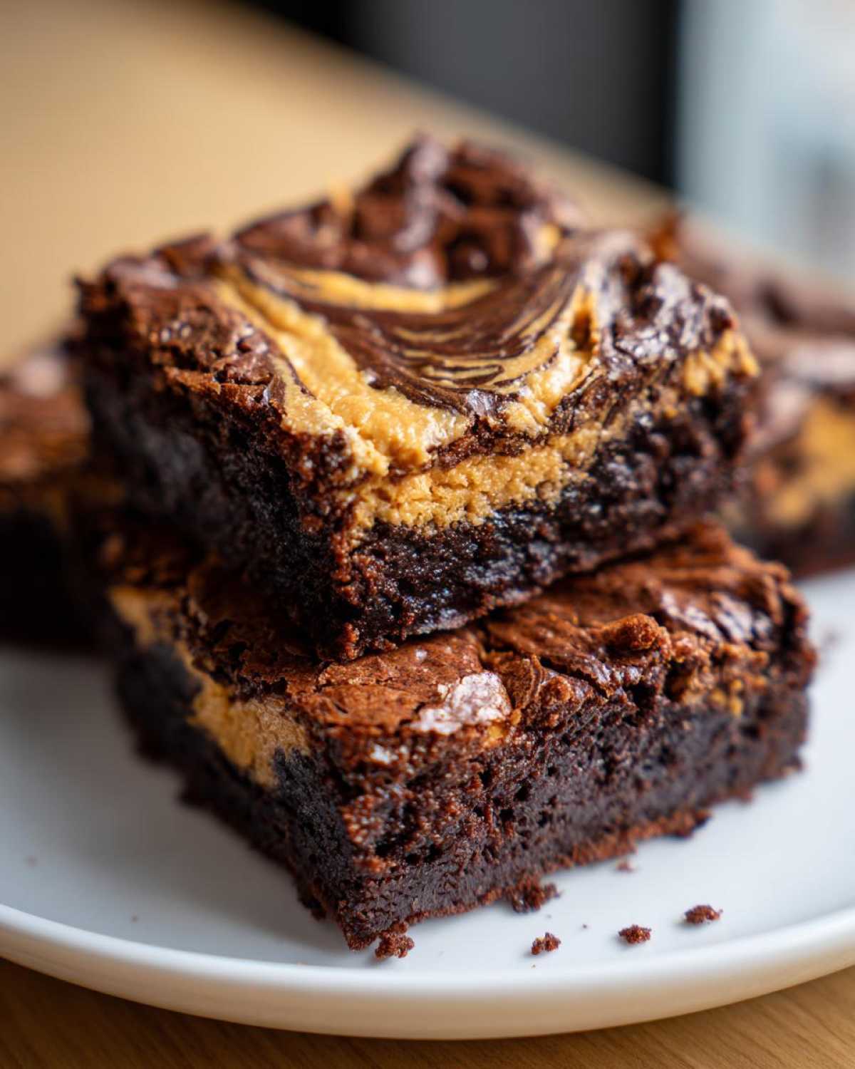 Close-up of two fudgy peanut butter swirl brownies stacked on a white plate, showing rich chocolate texture.