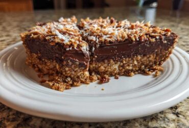 A rich slice of German chocolate pie showing a thick chocolate layer and a coconut-pecan crust, topped with toasted coconut.