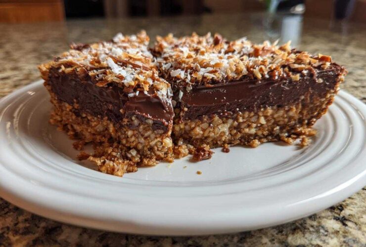 A rich slice of German chocolate pie showing a thick chocolate layer and a coconut-pecan crust, topped with toasted coconut.