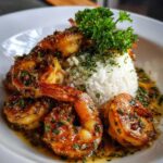 A plate featuring juicy, glazed hawaiian garlic shrimp served alongside white rice and garnished with fresh parsley.