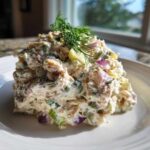 A mound of creamy healthy tuna salad mixed with red onion and celery, topped with fresh dill.