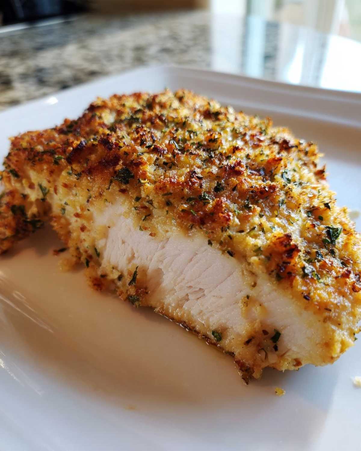 Cross-section of juicy baked ranch chicken showing a golden, herbed crust and moist white meat inside.