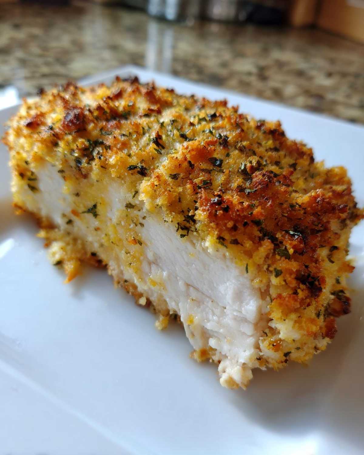Cross section of juicy baked ranch chicken showing the white interior and crispy, golden-brown ranch coating.