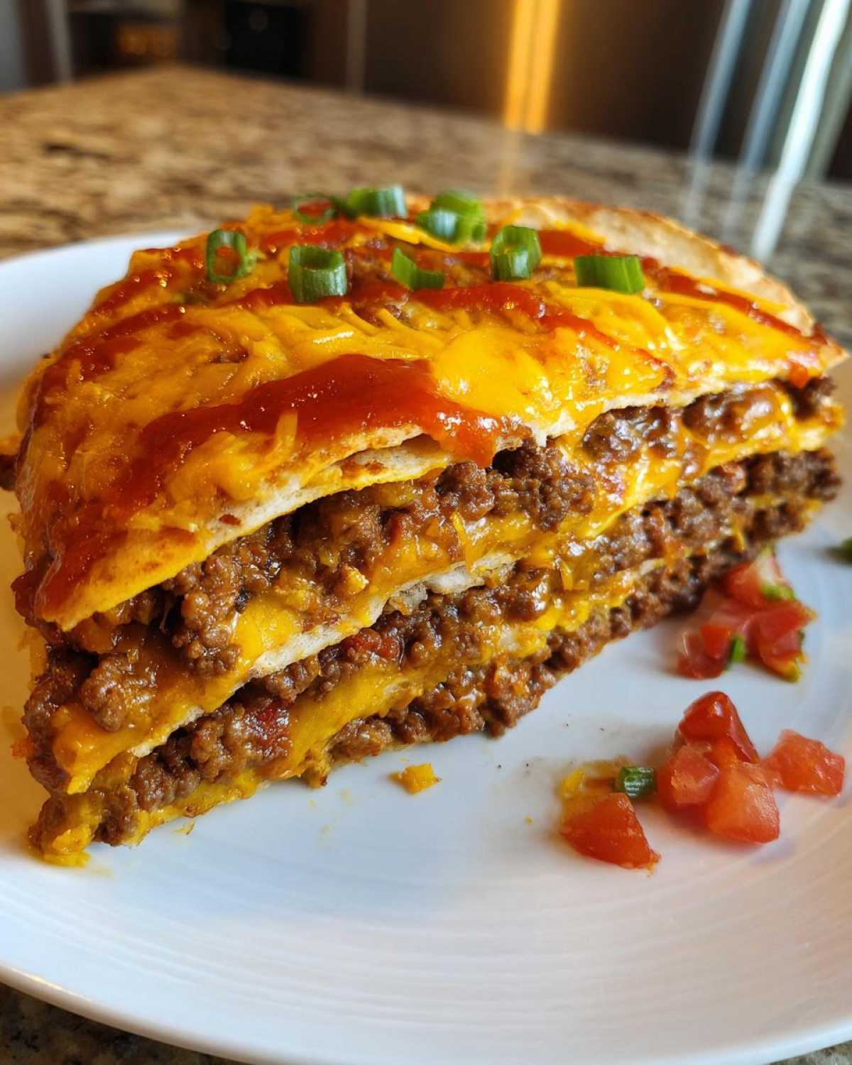 A thick, layered slice of Mexican pizza featuring seasoned ground beef, melted cheese, and sauce, topped with green onions.