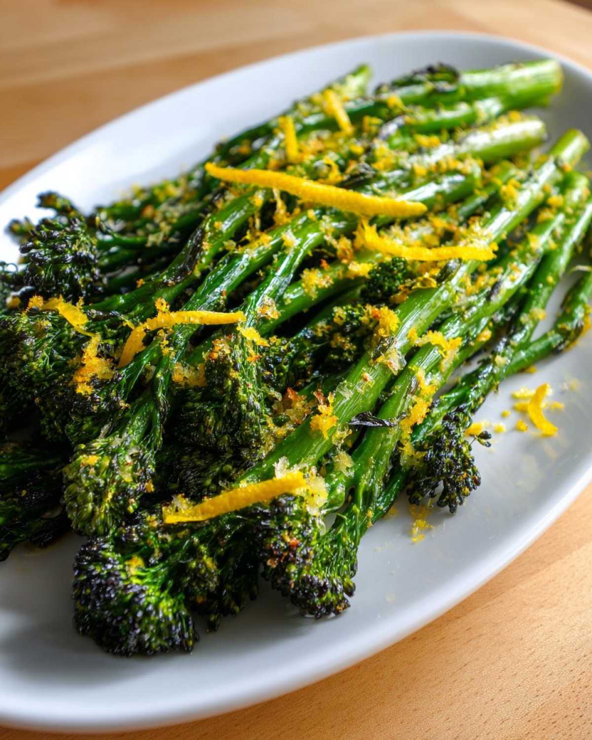 Close-up of vibrant green broccolini topped with bright yellow lemon zest and seasoning.