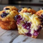 Close-up of moist blueberry cream cheese muffins, with one muffin cut open revealing the filling.