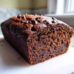 Close-up of a rich, dark chocolate banana bread loaf topped with melted chocolate chips.
