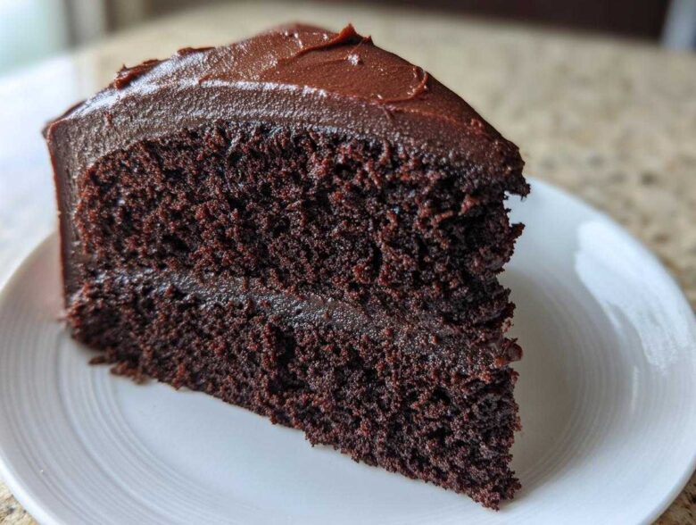 Close-up of a thick slice of moist chocolate cake layered with dark chocolate frosting.