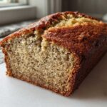 A freshly baked loaf of greek yogurt banana bread, showing a moist crumb texture and golden brown crust.