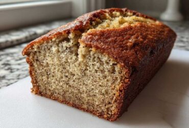 A freshly baked loaf of greek yogurt banana bread, showing a moist crumb texture and golden brown crust.