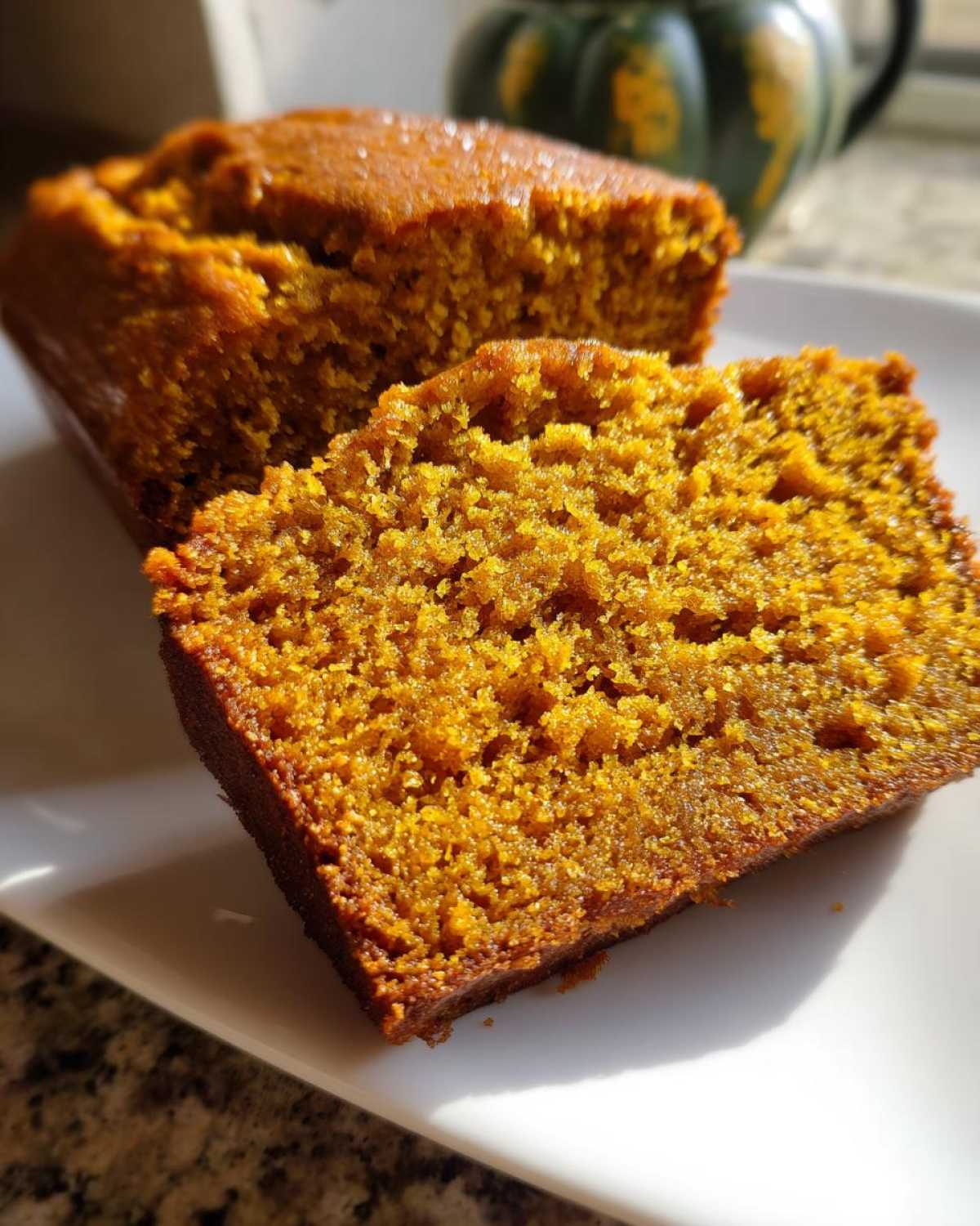 Close-up of a thick, moist slice of bright orange pumpkin bread showing its crumb texture.