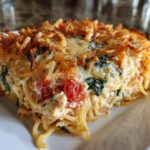 A close-up serving of baked monterey chicken spaghetti casserole with a crispy topping.