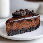 A decadent slice of rich chocolate cheesecake with a dark chocolate ganache and Oreo cookie crumble topping.
