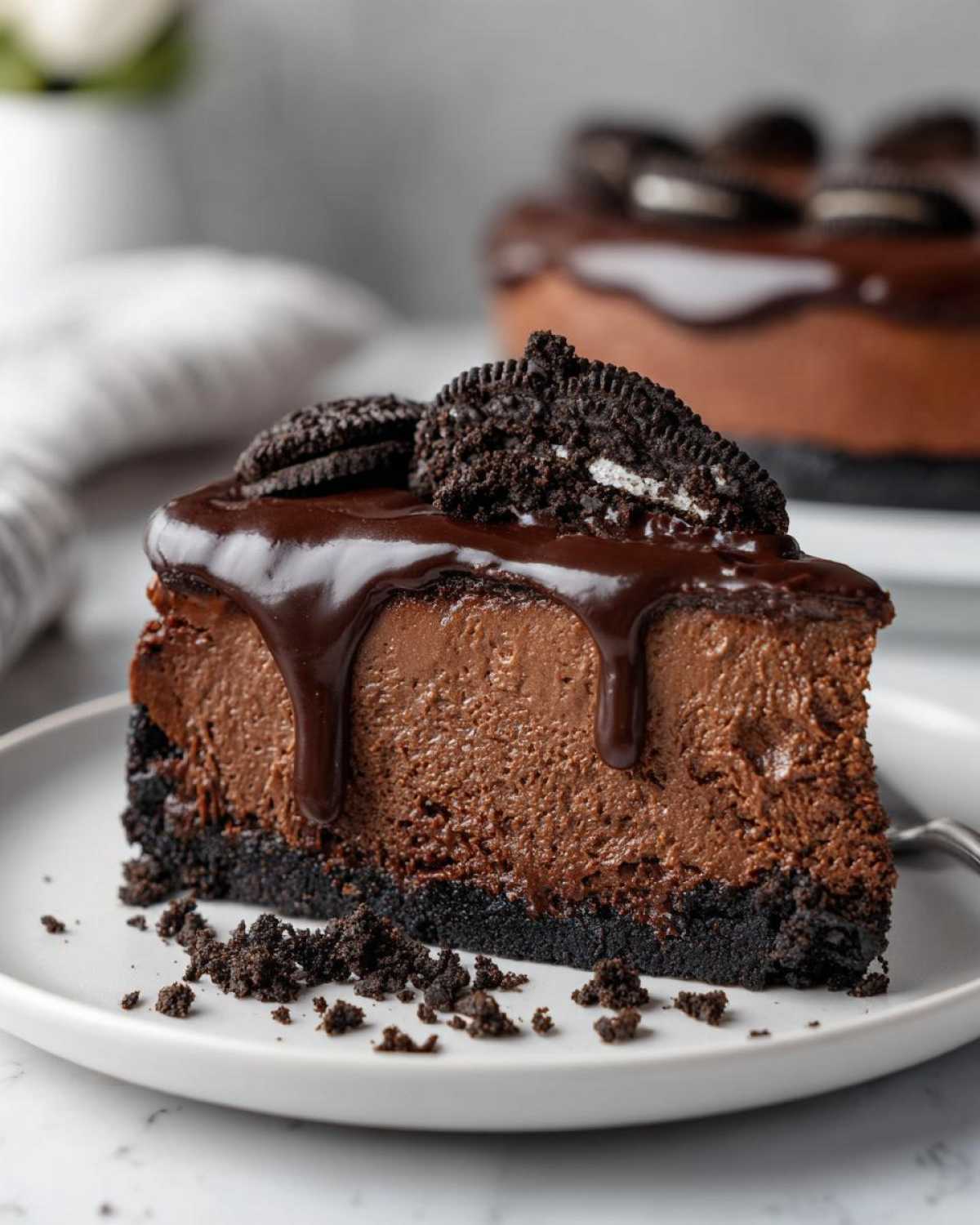 A decadent slice of rich chocolate cheesecake with a thick chocolate ganache drip and Oreo cookie garnish.