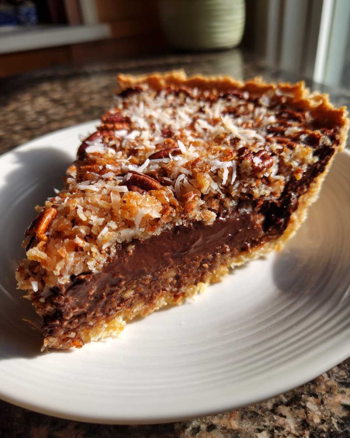 A close-up slice of German chocolate pie showing a rich chocolate filling and coconut pecan topping.