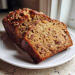Close-up of sliced sweet alabama pecan bread showing moist crumb and pecan topping.