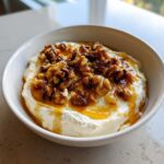 A close-up of sweet whipped ricotta dip topped generously with glazed walnuts and drizzled honey.