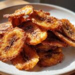 A close-up of crispy Air Fryer Crispy Cinnamon Sugar Banana Chips piled on a light gray plate.