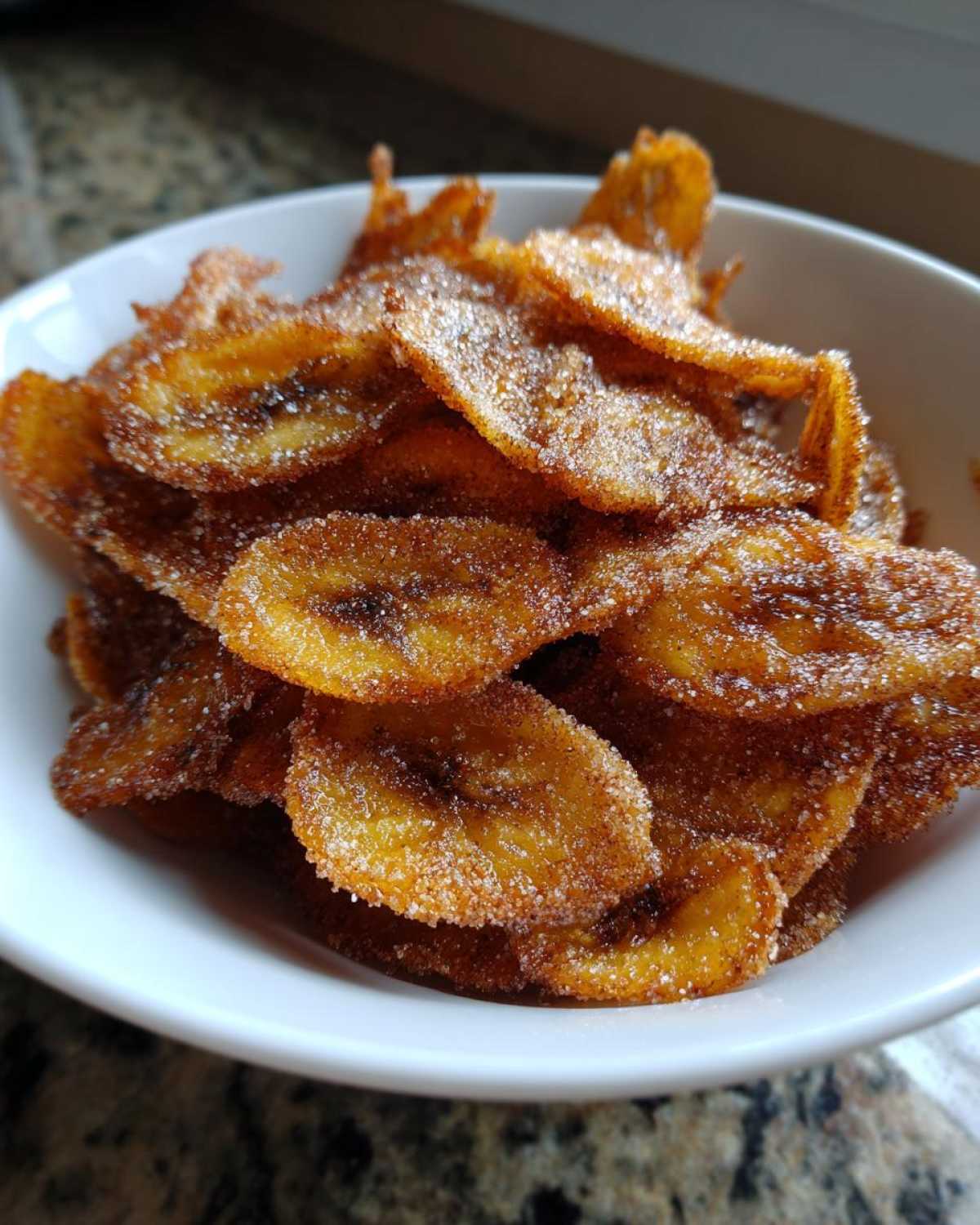 Close-up of crispy Air Fryer Crispy Cinnamon Sugar Banana Chips piled high in a white bowl.