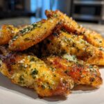 A close-up of golden brown Air Fryer Crispy Garlic Parmesan Chicken Wings piled high on a white plate.