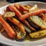 Close-up of perfectly caramelized roasted vegetables, including carrots and onions, seasoned with herbs.