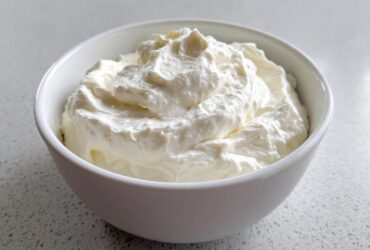 A close-up of fluffy, white creamy horseradish sauce swirled high in a small white bowl.