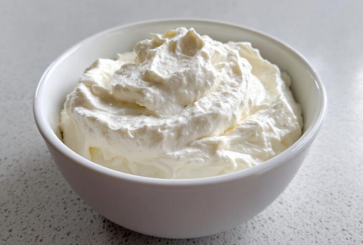 A close-up of fluffy, white creamy horseradish sauce swirled high in a small white bowl.
