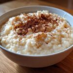 A close-up of a creamy bowl of rice pudding recipe, generously sprinkled with ground cinnamon.