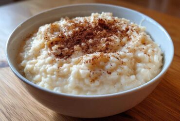 A close-up of a creamy bowl of rice pudding recipe, generously sprinkled with ground cinnamon.