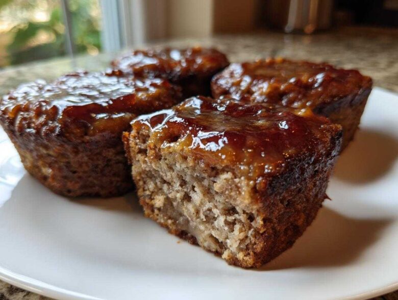 Close-up of four individual mini meatloaf portions, one cut open, showing a thick, shiny glaze.