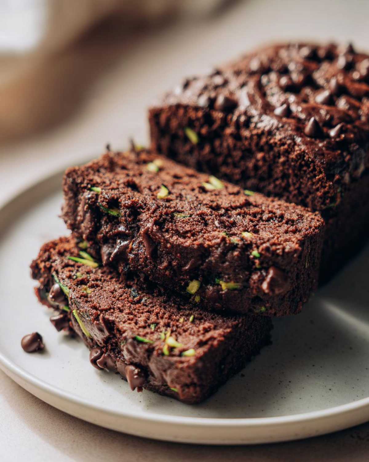 Close-up of moist slices of Gluten-Free Chocolate Zucchini Bread studded with chocolate chips and visible green zucchini shreds.
