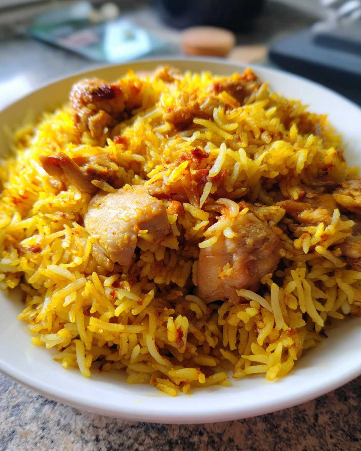 Close-up of a white bowl filled with vibrant yellow Instant Pot Chicken Shawarma Rice and seasoned chicken pieces.