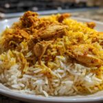 Close-up of a white plate filled with fluffy white and yellow seasoned rice topped with tender pieces of seasoned chicken for Instant Pot Chicken Shawarma Rice.