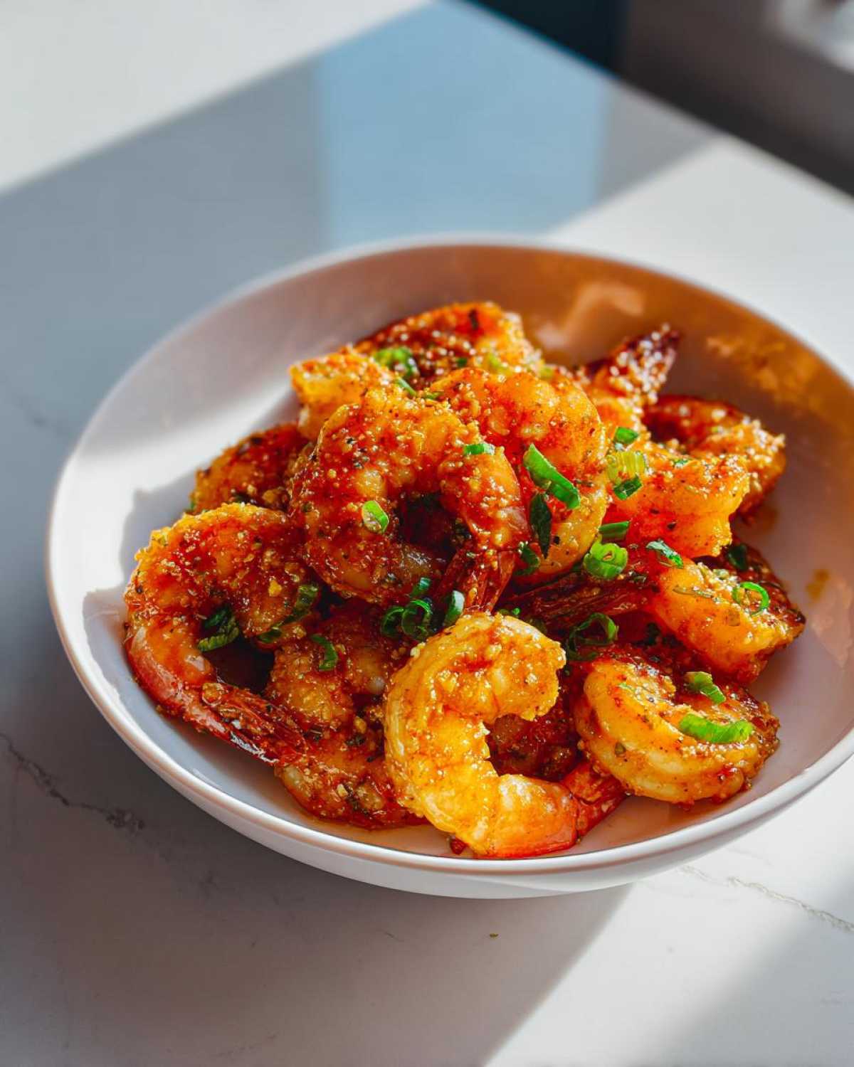 Close-up of Instant Pot Creamy Garlic Butter Shrimp Scampi garnished with green onions in a white bowl.