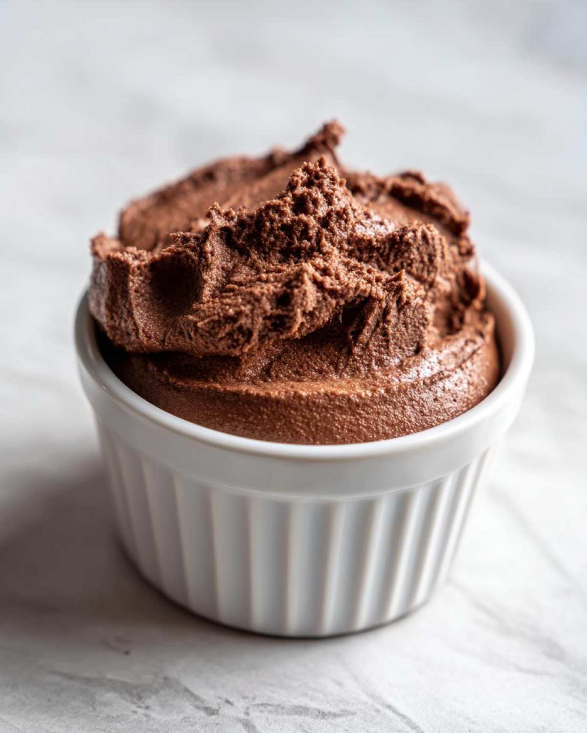 A close-up of rich, dark Keto Creamy Chocolate Cheesecake Mousse served in a white fluted ramekin.