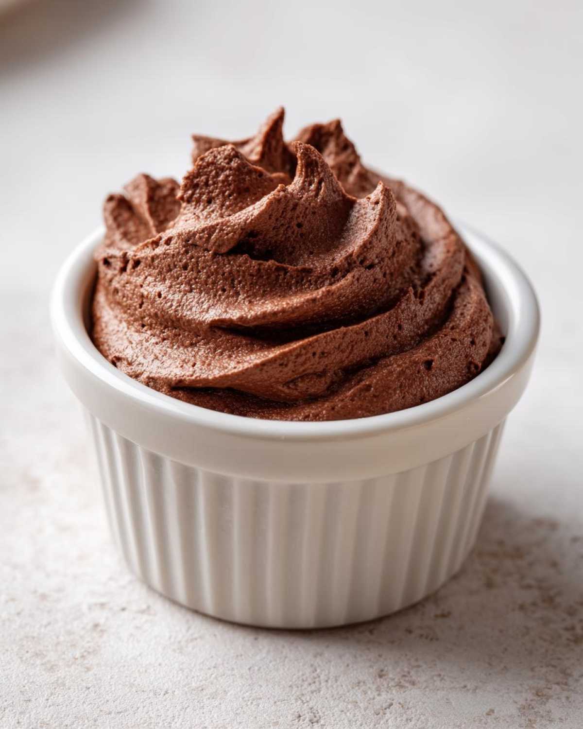 A single serving of rich, dark Keto Creamy Chocolate Cheesecake Mousse piped high in a white ramekin.