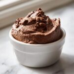 A close-up of rich, dark brown Keto Creamy Chocolate Cheesecake Mousse served in a small white ramekin.