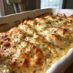 Close-up of Keto Creamy Garlic Herb Chicken Bake with melted, browned cheese and herbs in a white casserole dish.