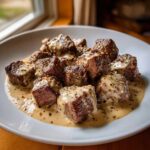 Close-up of Keto Creamy Peppercorn Steak Bites smothered in a rich, creamy sauce with whole peppercorns.