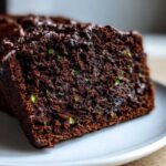 Close-up of a moist slice of dark chocolate Gluten-Free Chocolate Zucchini Bread showing green zucchini flecks.