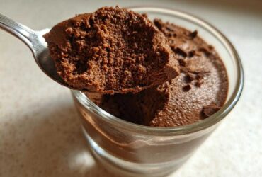 A spoonful of rich, airy chocolate mousse being lifted from a glass cup.