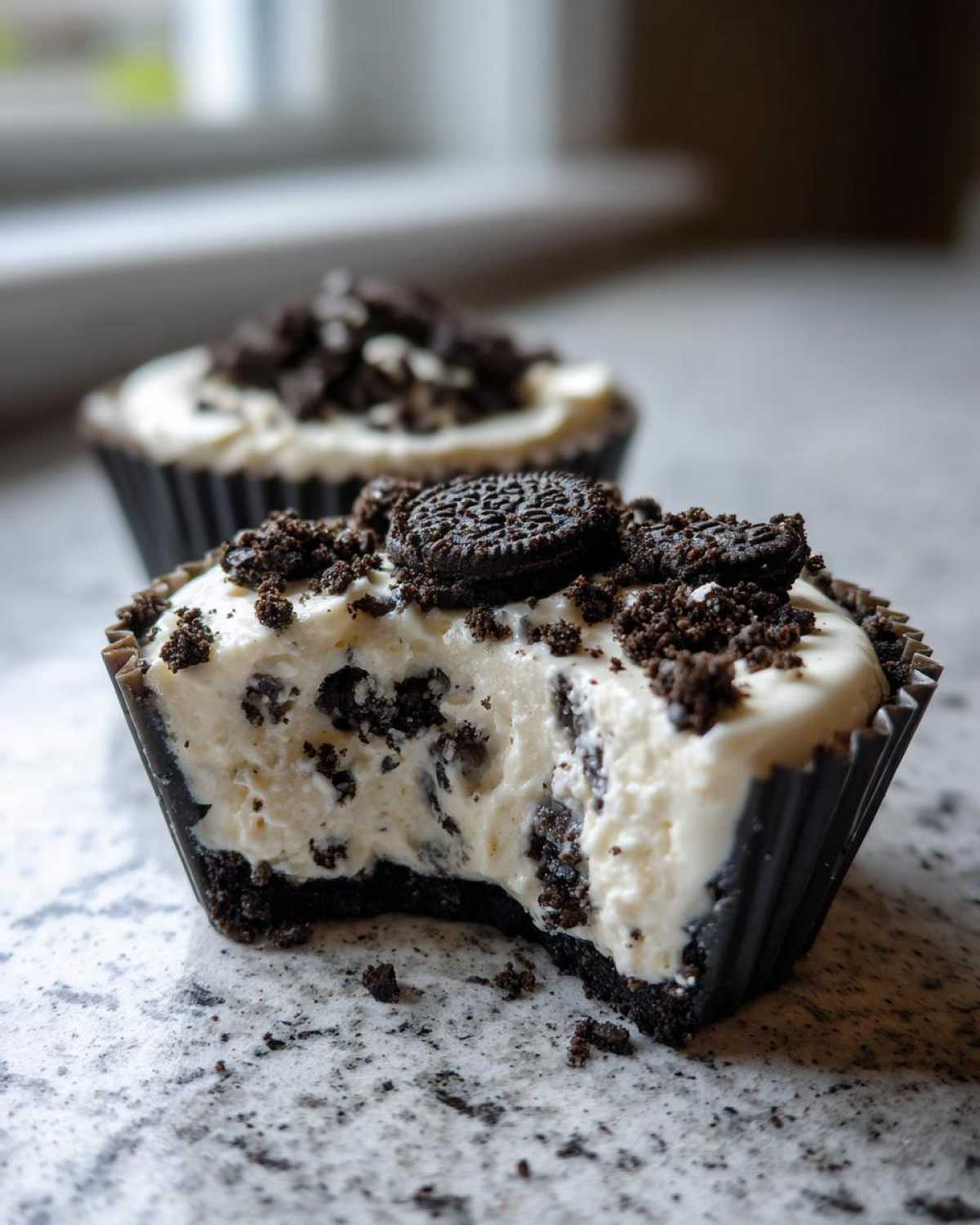 A close-up view of a No-Bake Cookies and Cream Pie Cup with a bite taken out, showing the creamy filling and cookie crust.