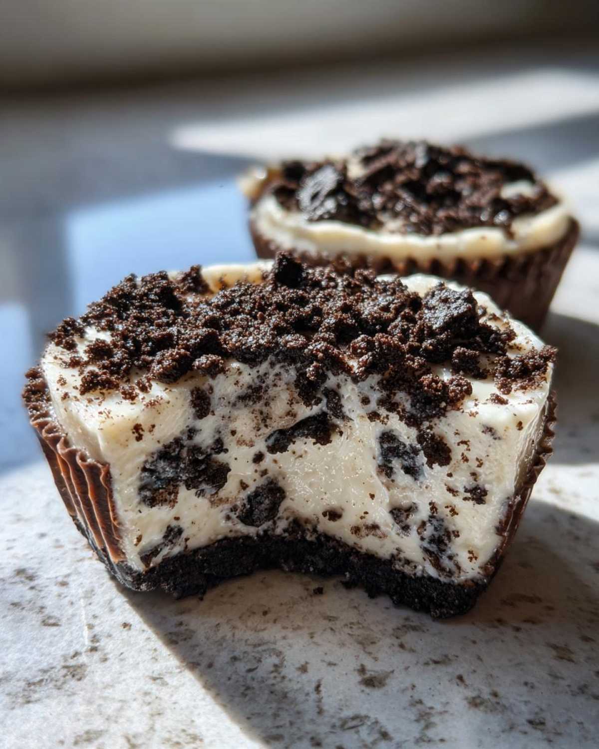 A close-up of a No-Bake Cookies and Cream Pie Cups with a bite taken out, showing the creamy filling and cookie crust.
