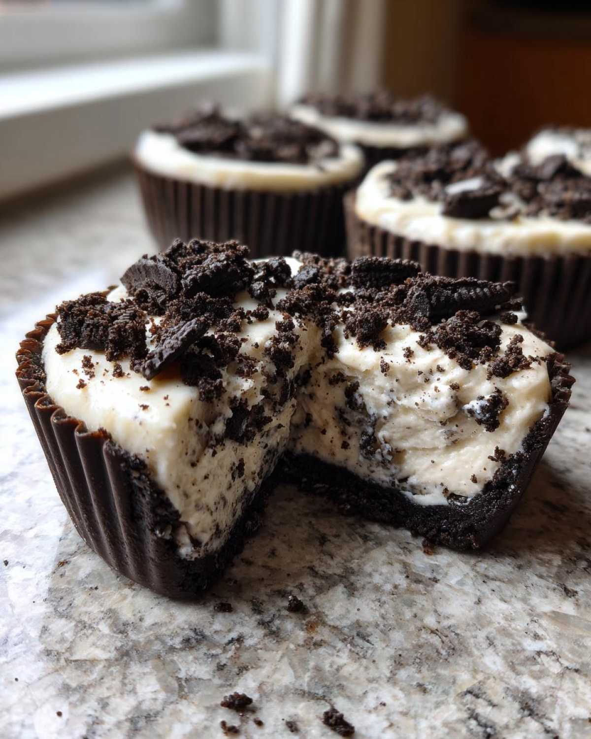 A close-up view of a No-Bake Cookies and Cream Pie Cup cut in half, showing the creamy filling and cookie crust.