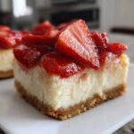 Close-up of a thick slice of No-Bake Strawberry Lemon Cheesecake Bars with a graham cracker crust and fresh strawberry topping.