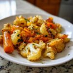 Close-up of perfectly roasted vegetables, including cauliflower florets and carrots, seasoned and garnished with parsley.