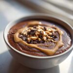 Close-up of a thick Vegan Chocolate Peanut Butter Banana Smoothie Bowl topped with peanut butter drizzle, chopped peanuts, and chocolate chunks.
