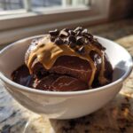 A scoop of thick Vegan Chocolate Peanut Butter Banana Smoothie Bowl topped with peanut butter drizzle and chocolate chips.