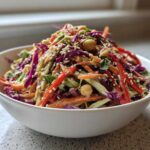 Close-up of a vibrant Asian Chickpea Slaw featuring shredded cabbage, carrots, chickpeas, and sesame seeds.